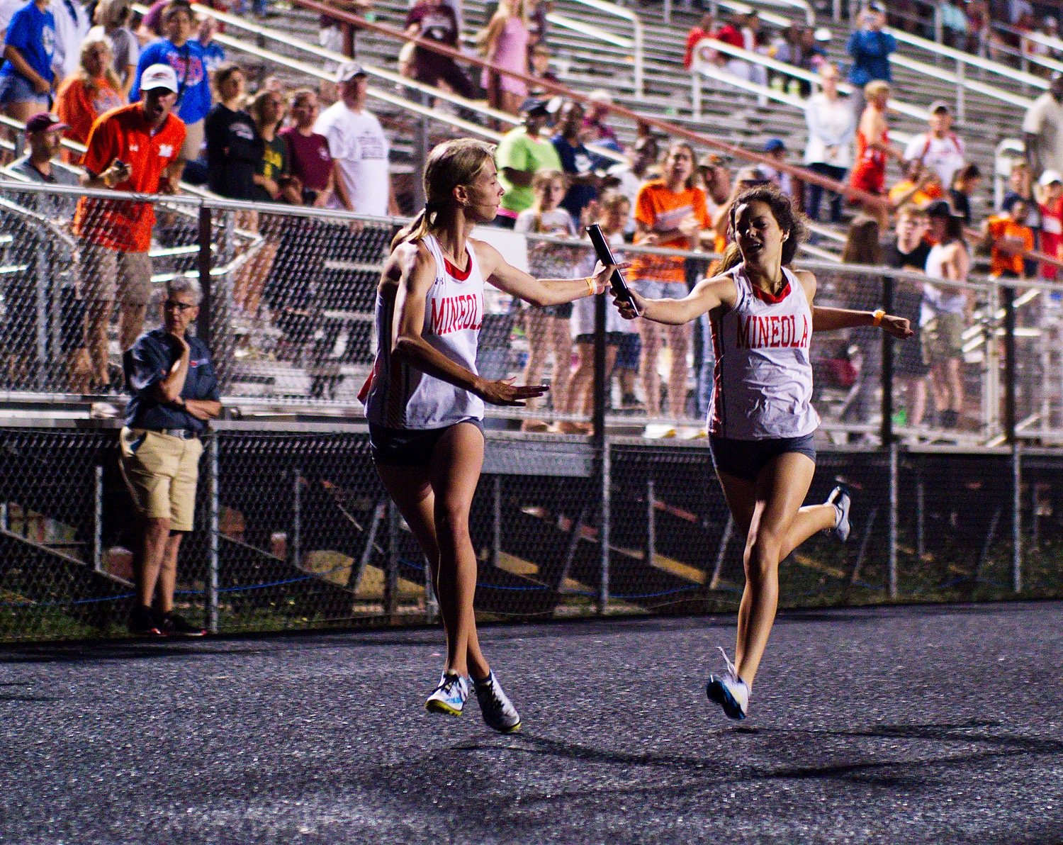 Kozbie Riley hands the baton off to Olivia Hughes for the second leg of Mineola's 4x400m relay final. [see more sprinters, soarers]